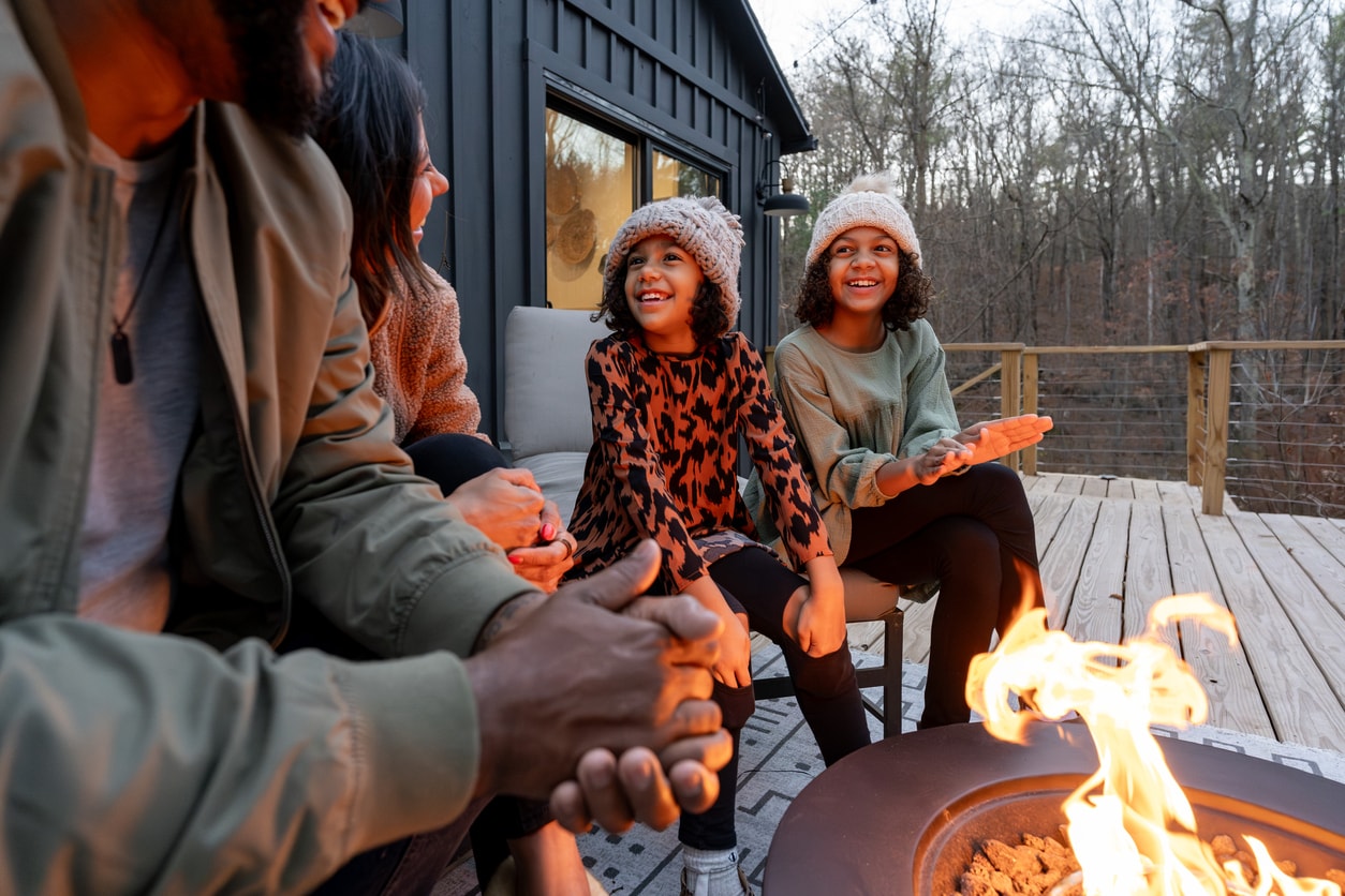 A photo of a family gathered around a fire pit on a chilly evening.